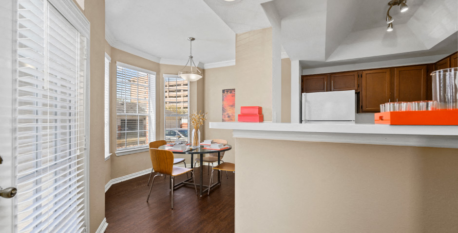Spacious dining room with 9-foot ceilings, oversized windows, French door and wood grain plank flooring and kitchen with recessed ceiling at The Lanesborough Apartments in Houston.