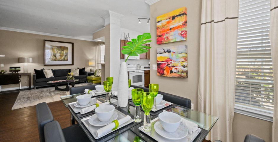 Spacious living room and dining room with wood-burning fireplace with glass doors, ceiling fan, 9-foot ceilings and wood grain plank flooring at The Lanesborough Apartments in Houston.
