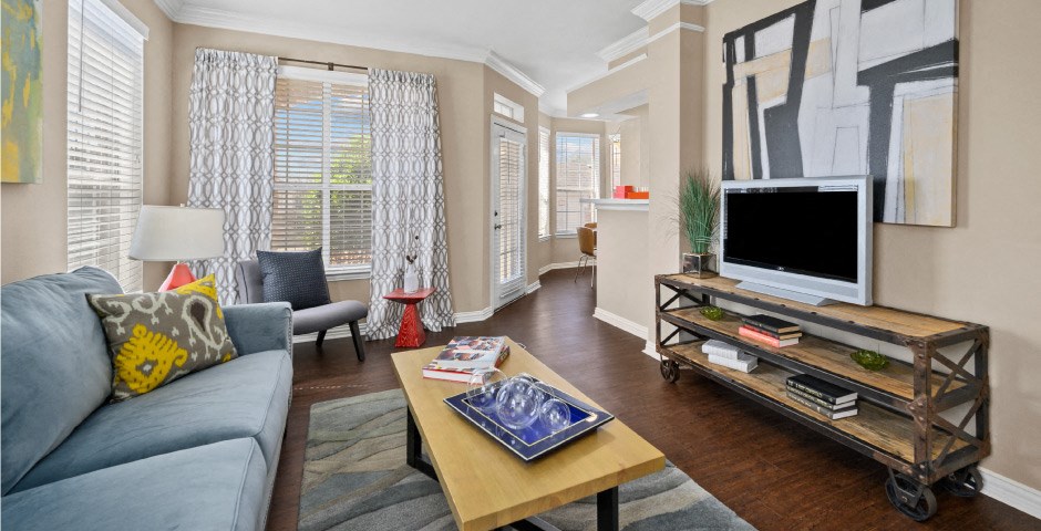 Spacious living room and dining room with 9-foot ceilings, oversized windows, French door and wood grain plank flooring at The Lanesborough Apartments in Houston.