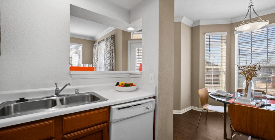 Spacious dining room with 9-foot ceilings, oversized windows, French door and wood grain plank flooring and kitchen with recessed ceiling at The Lanesborough Apartments in Houston.