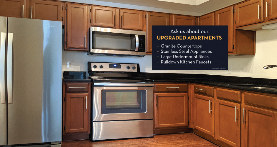 Luxury apartments with spacious kitchens, black granite countertops, stainless steel appliances, honey brown toned cabinets, and side-by-side refrigerators at The Lanesborough Apartments in Houston