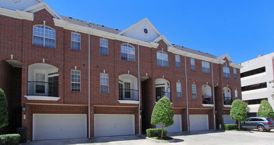 Luxury townhomes with red brick exteriors and attached 2-car garages at Tuscany Villas in Houston.