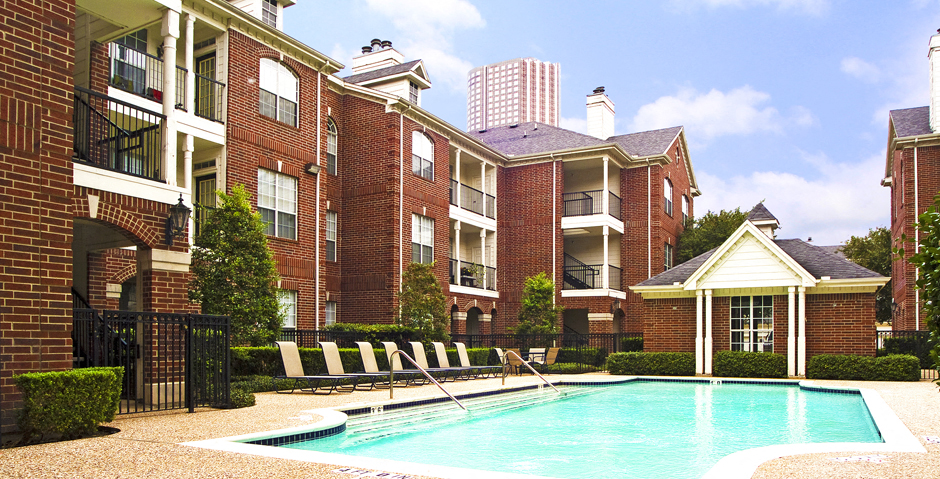 Luxury swimming pool with spacious sundeck, beautiful landscaping, and pool-side lounge seating at Tuscany Lane Apartments in Houston.