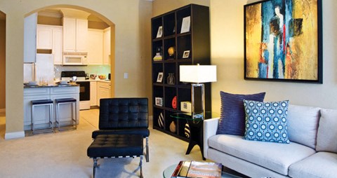 Spacious living room and bright kitchen with white cabinets at Tuscany Court Apartments in Houston.