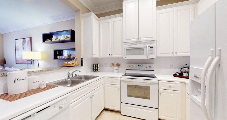 Bright kitchen with granite slab breakfast bar and white cabinets at Tuscany Court Apartments in Houston.