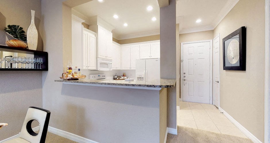 Bright kitchen with granite slab breakfast bar, spacious kitchen with white cabinets at Tuscany Court Apartments in Houston.