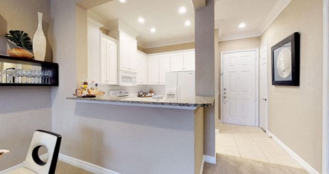 Bright kitchen with granite slab breakfast bar, spacious kitchen with white cabinets at Tuscany Court Apartments in Houston.