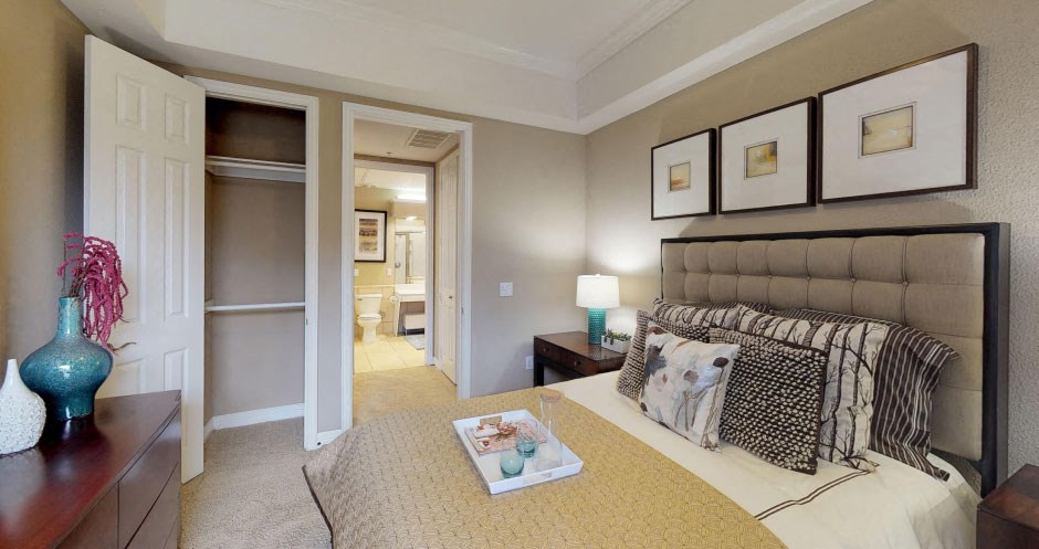 Spacious bedroom with walk-in closet, ceiling fan, and recessed ceiling at Tuscany Court Apartments in Houston.
