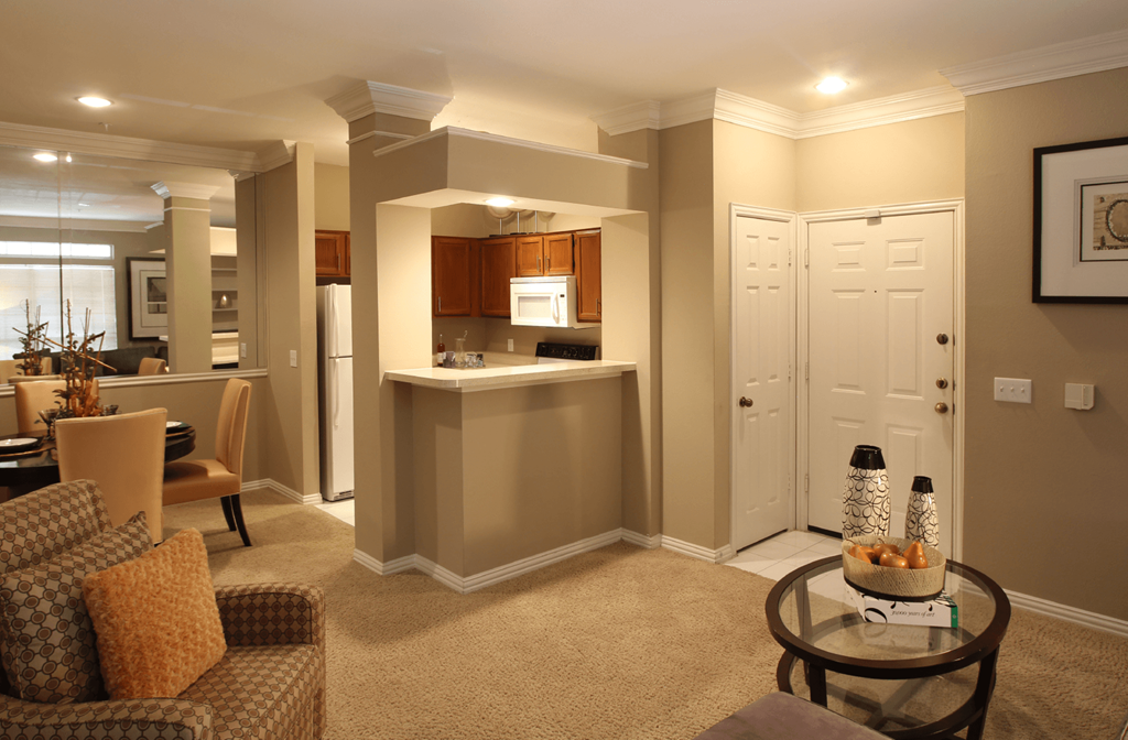 Spacious kitchen with custom home cabinets, breakfast bar, and mirror accent wall at Tuscany Park Apartments in Houston.