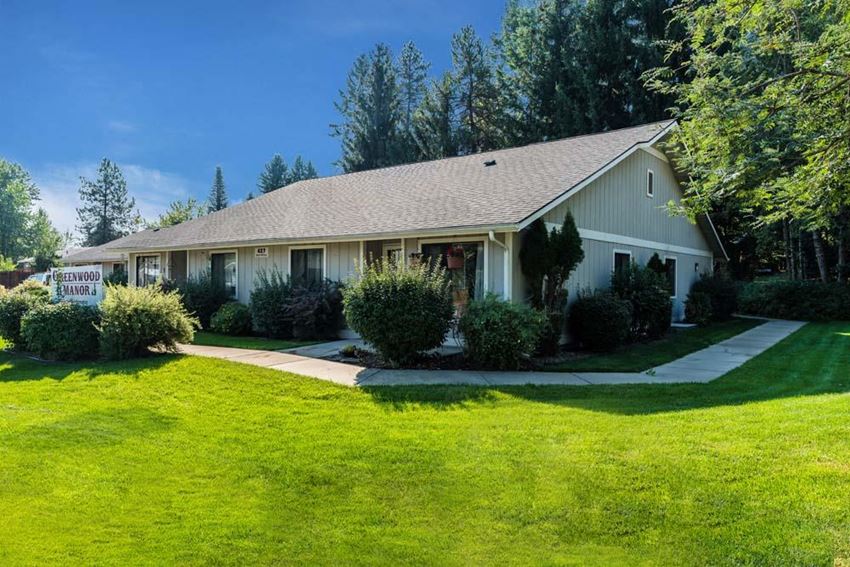 a white house with a green lawn and trees