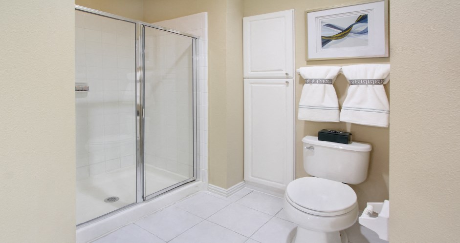 Luxury bathroom with tiled floors, glass shower, linen closet, and white cabinets in at TurtleCreek apartments in West Des Moines, Iowa
