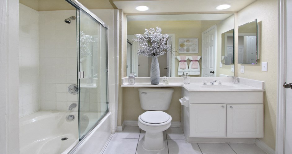 Luxury bathroom with tiled floors, oval soaking tub, built-in vanity, cultured marble vanity, glass shower and white cabinets in at TurtleCreek apartments in West Des Moines, Iowa
