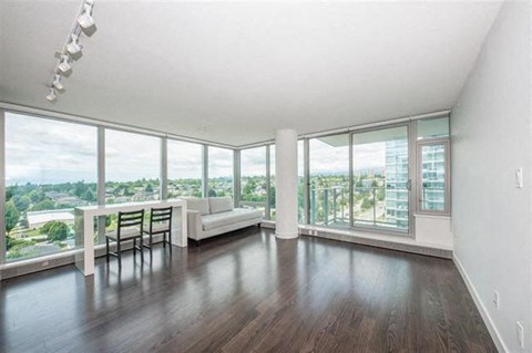 A spacious living room with a view of the cityscape outside the large windows.