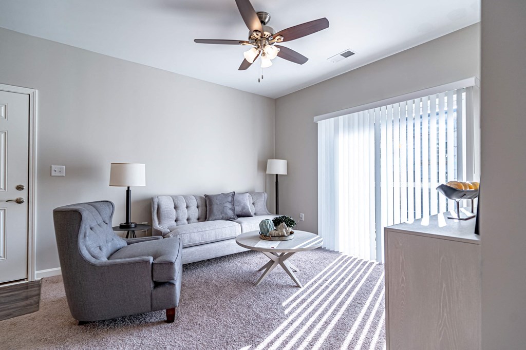 a living room with a couch and chair and a ceiling fan
