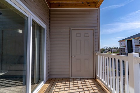 a porch with a white door and a balcony