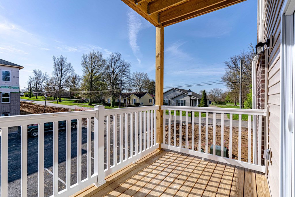 the deck of a house with a view of the street and trees