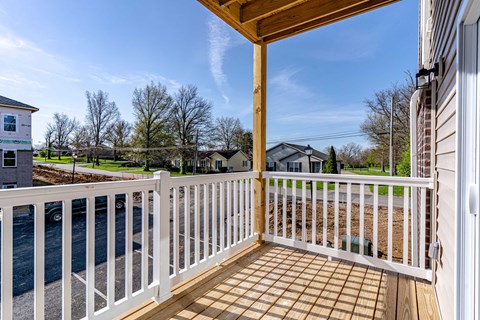 the deck of a house with a view of the street and trees