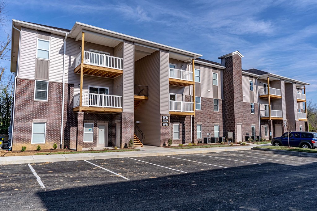 an exterior view of an apartment building with a parking lot