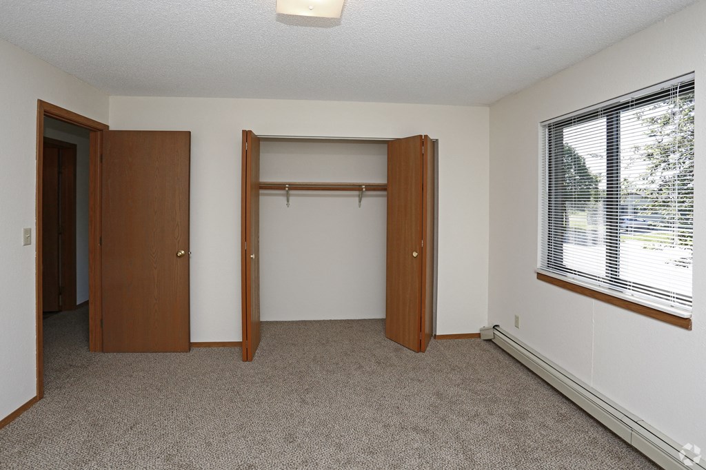an empty bedroom with a closet and a window