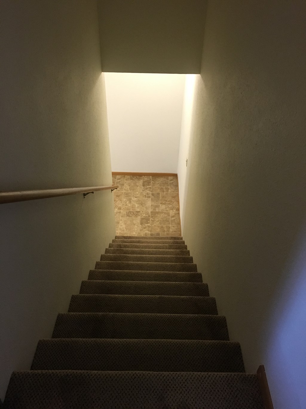 a stairwell leading up to a room with a stair railing and a white wall