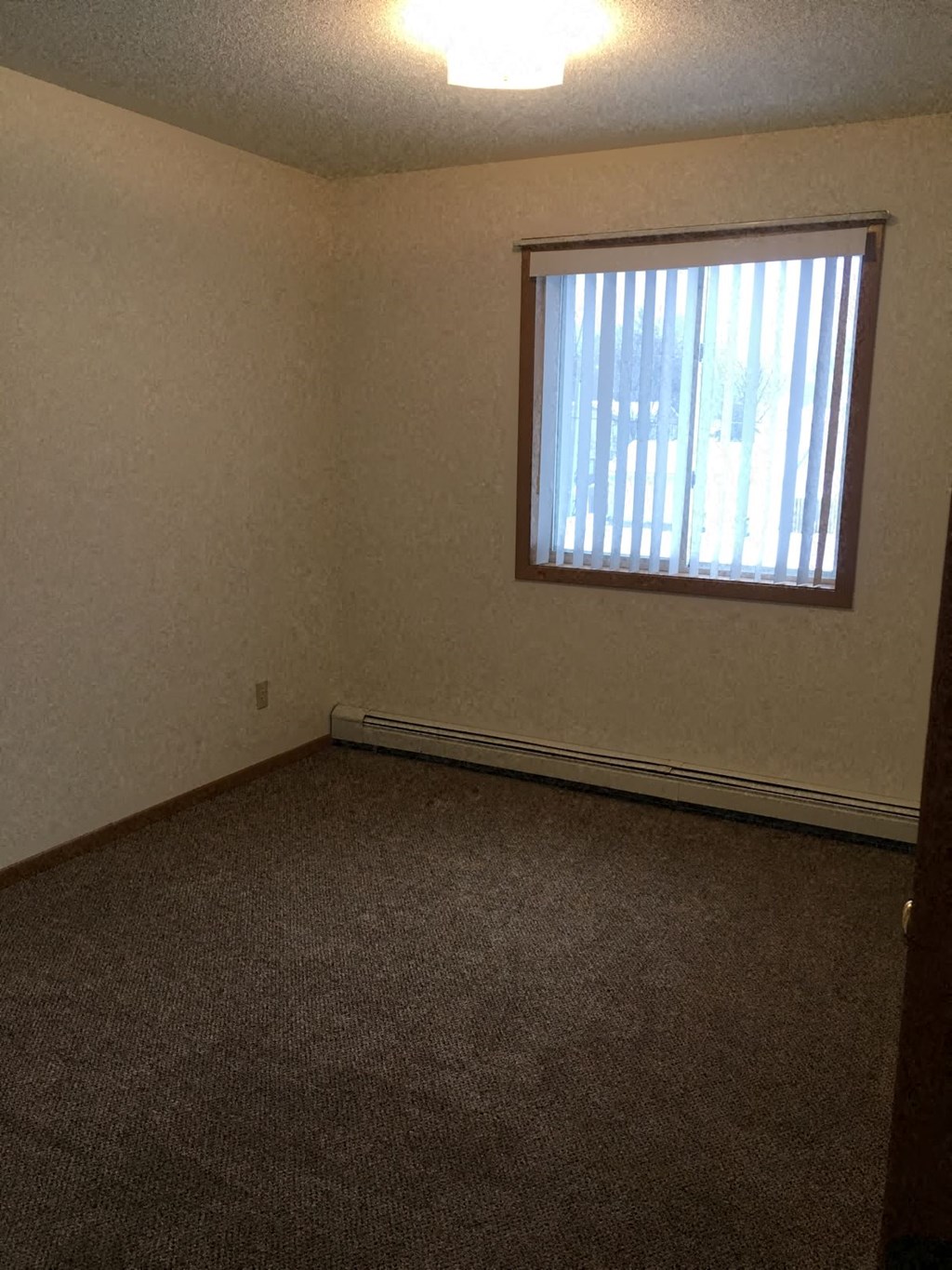 an empty room with a window and a carpet