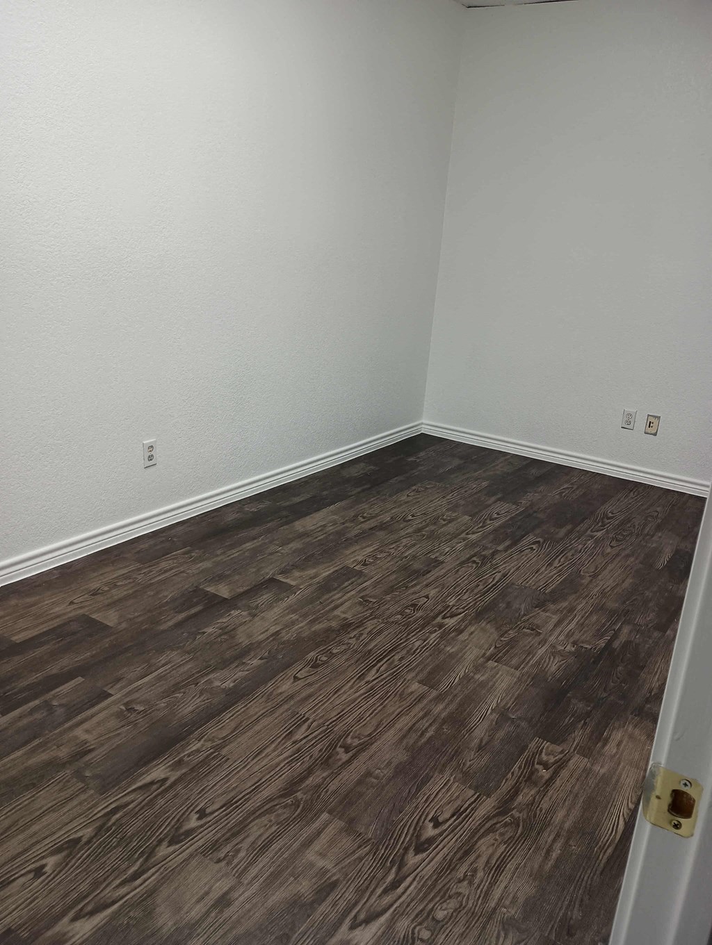 an empty room with wooden floors and white walls