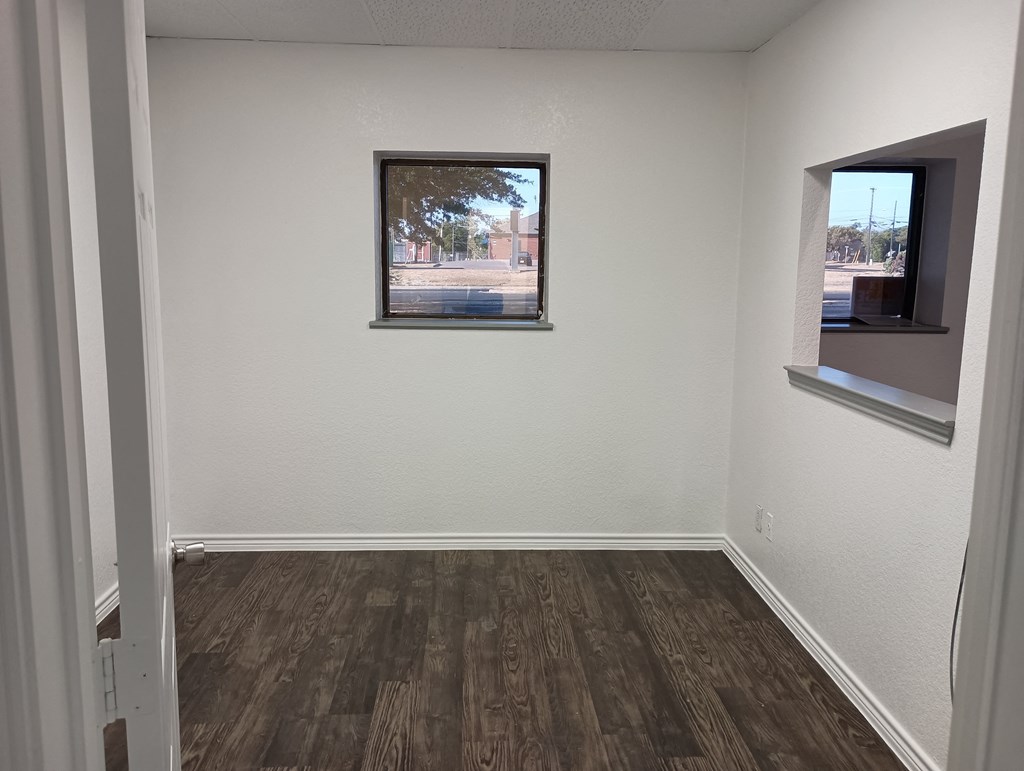 an empty room with a window and wooden floors