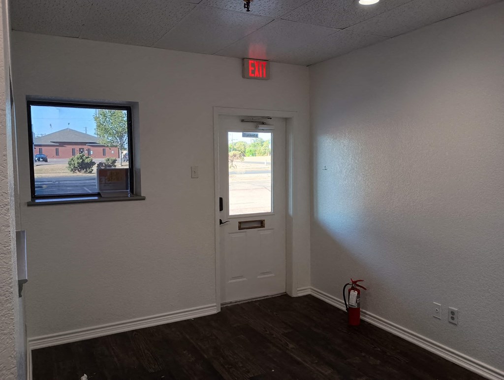 an empty room with an exit sign above a door and a window