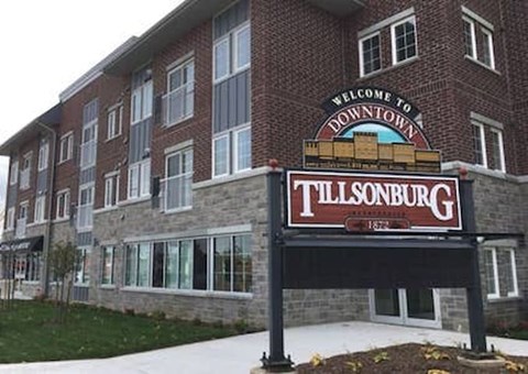 A sign welcoming people to Downtown Tillsonburg is displayed in front of a building.