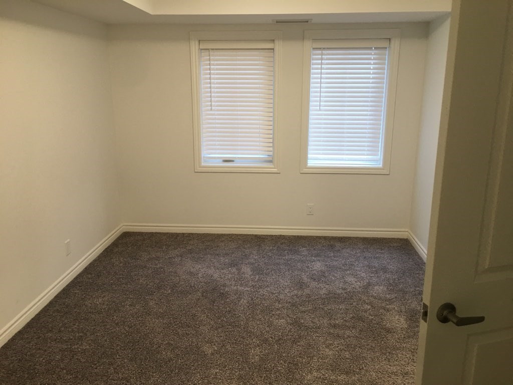 a room with a carpeted floor and two windows