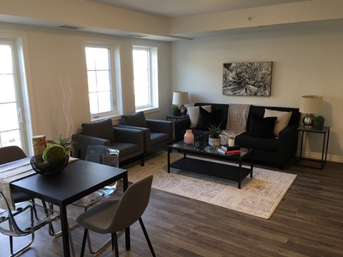 A living room with a black couch, a coffee table, and a dining table with chairs.