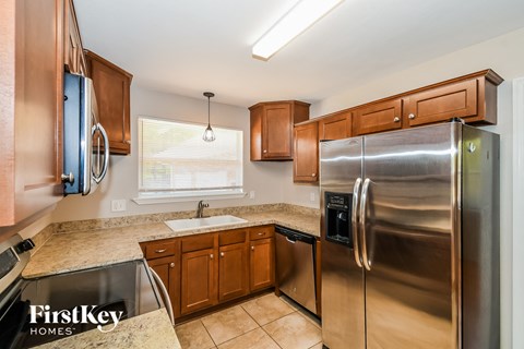 A kitchen with a stainless steel refrigerator and wooden cabinets.