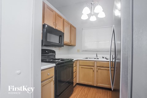 a kitchen with wooden cabinets and black appliances and a black refrigerator