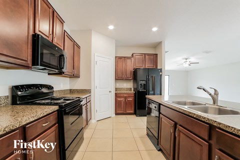 A kitchen with brown cabinets and a black stove top oven.