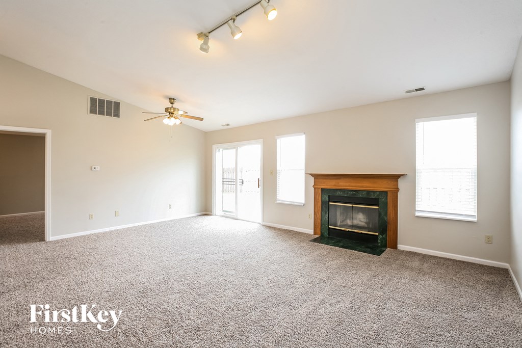 an empty living room with a fireplace and a ceiling fan