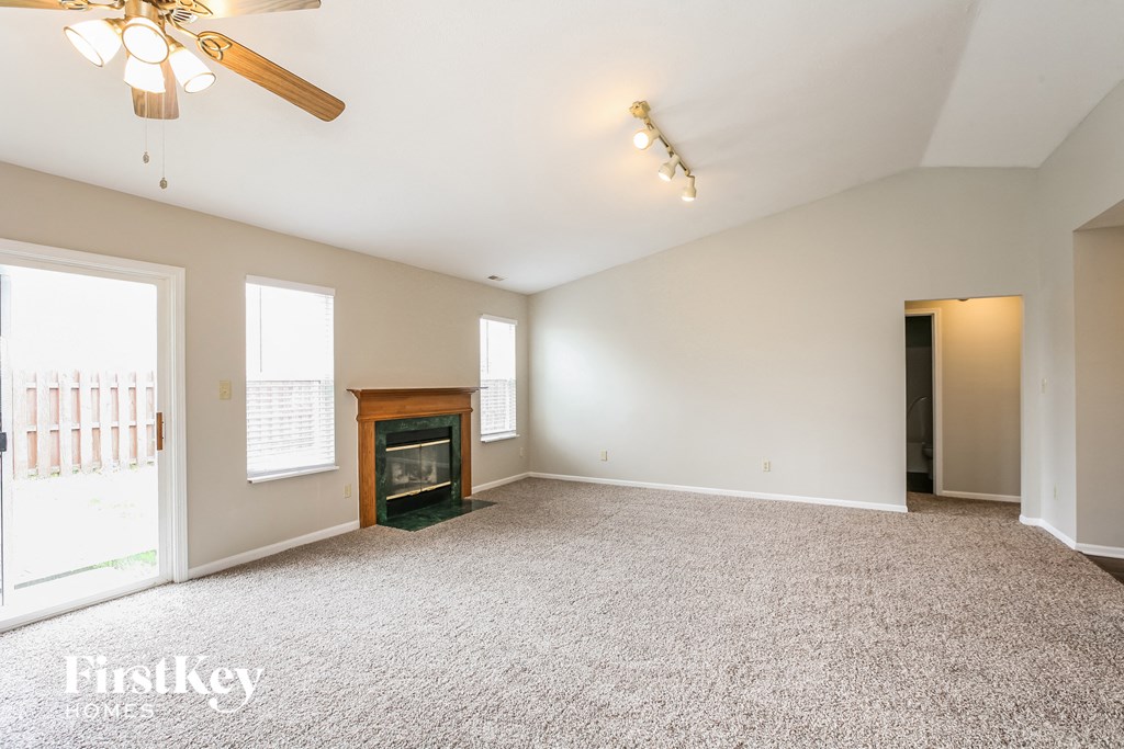 an empty living room with a fireplace and a ceiling fan