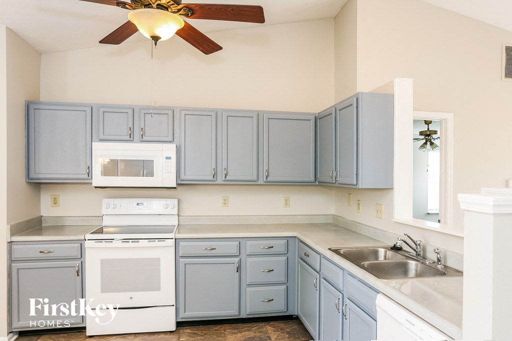 a kitchen with blue cabinets and white appliances and a ceiling fan