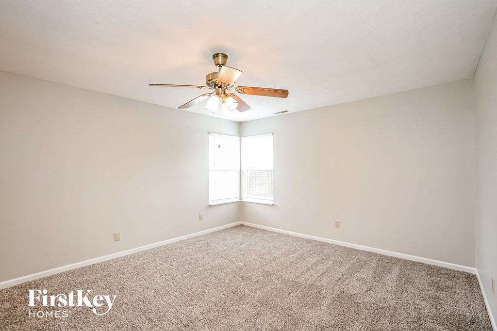 the spacious living room with ceiling fan and carpet
