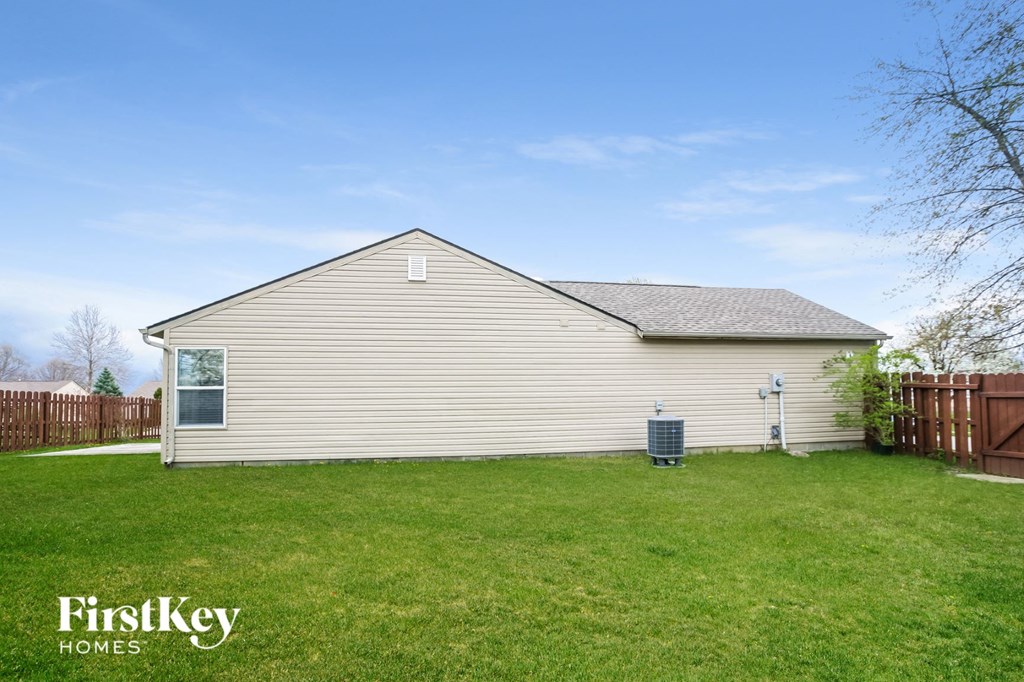the backyard of a house with a yard and a grill