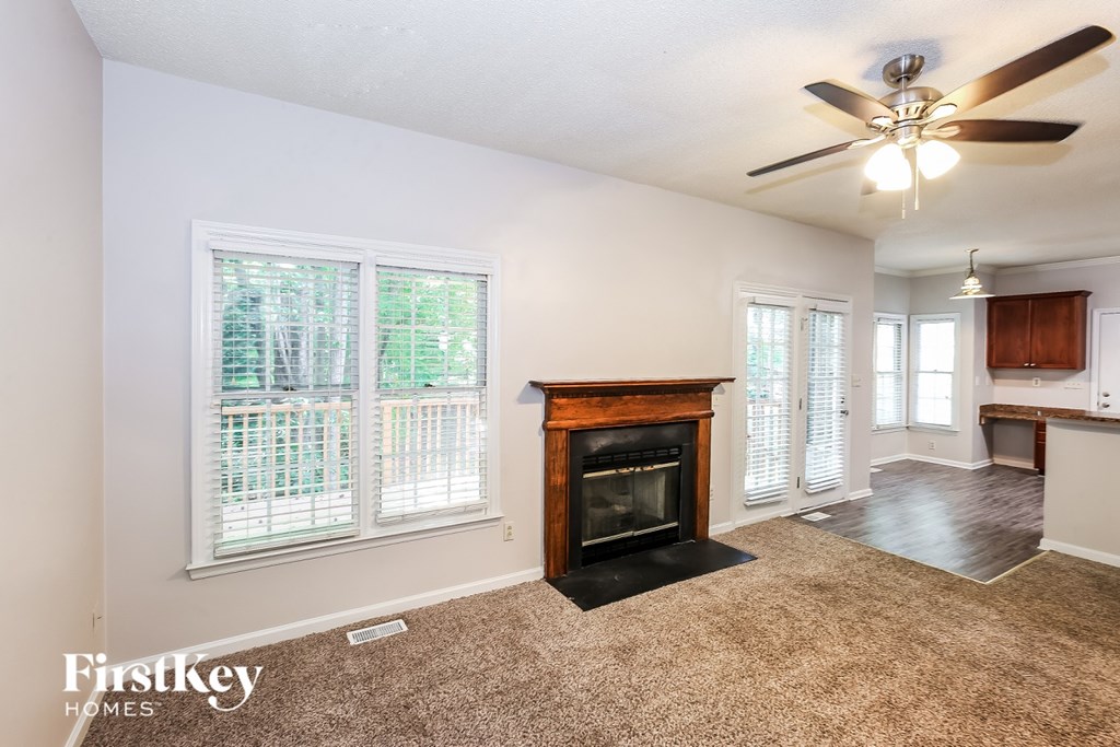 A living room with a fireplace and a ceiling fan.