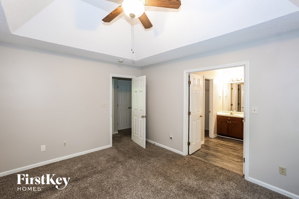 A spacious room with a ceiling fan and two doors.