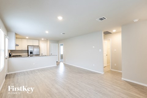 A spacious empty room with wooden flooring and white walls.