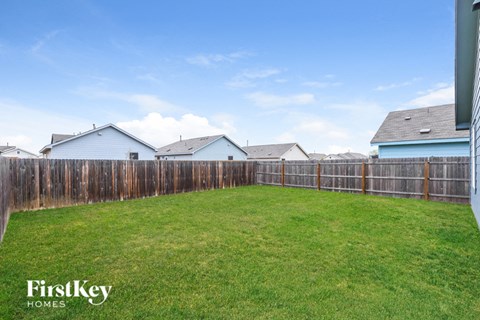 A backyard with a wooden fence and a grassy area.