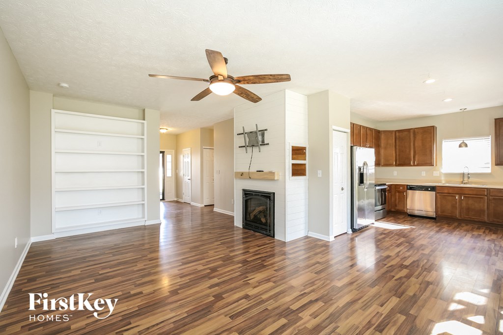 an empty living room with a wood floor and a ceiling fan