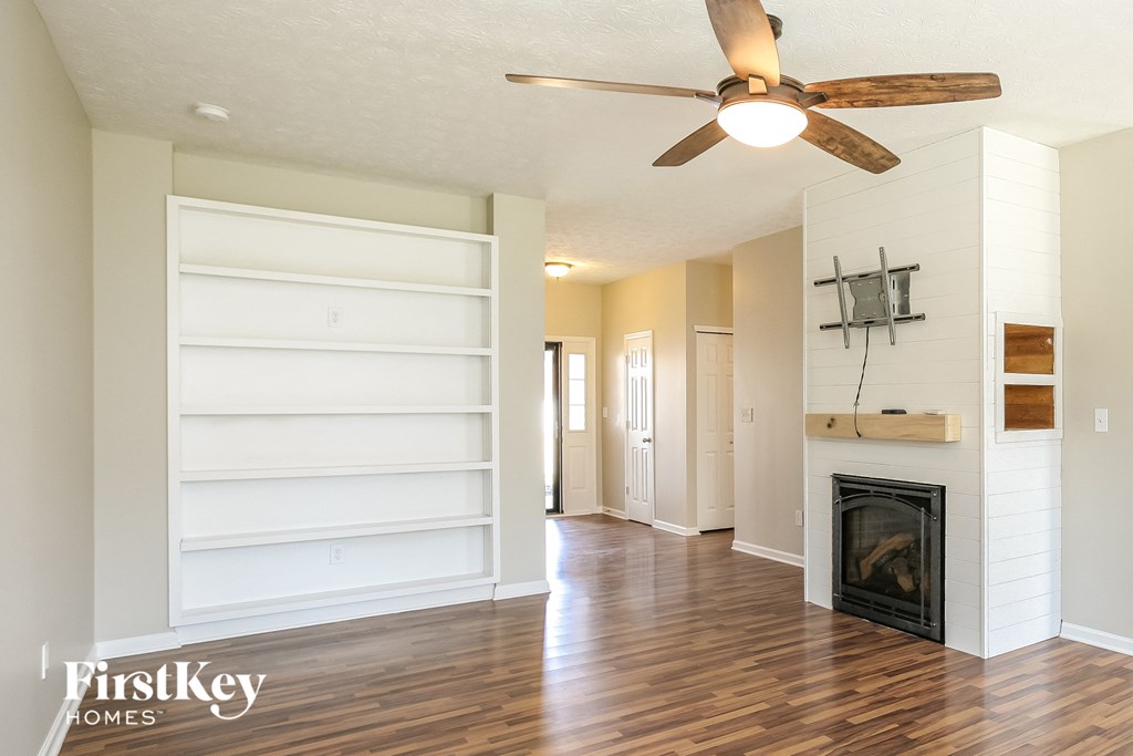 an empty living room with a ceiling fan and a fireplace