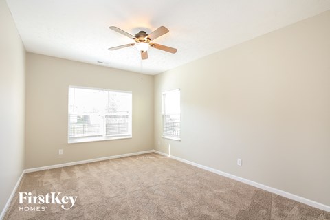 a spacious living room with carpet and a ceiling fan