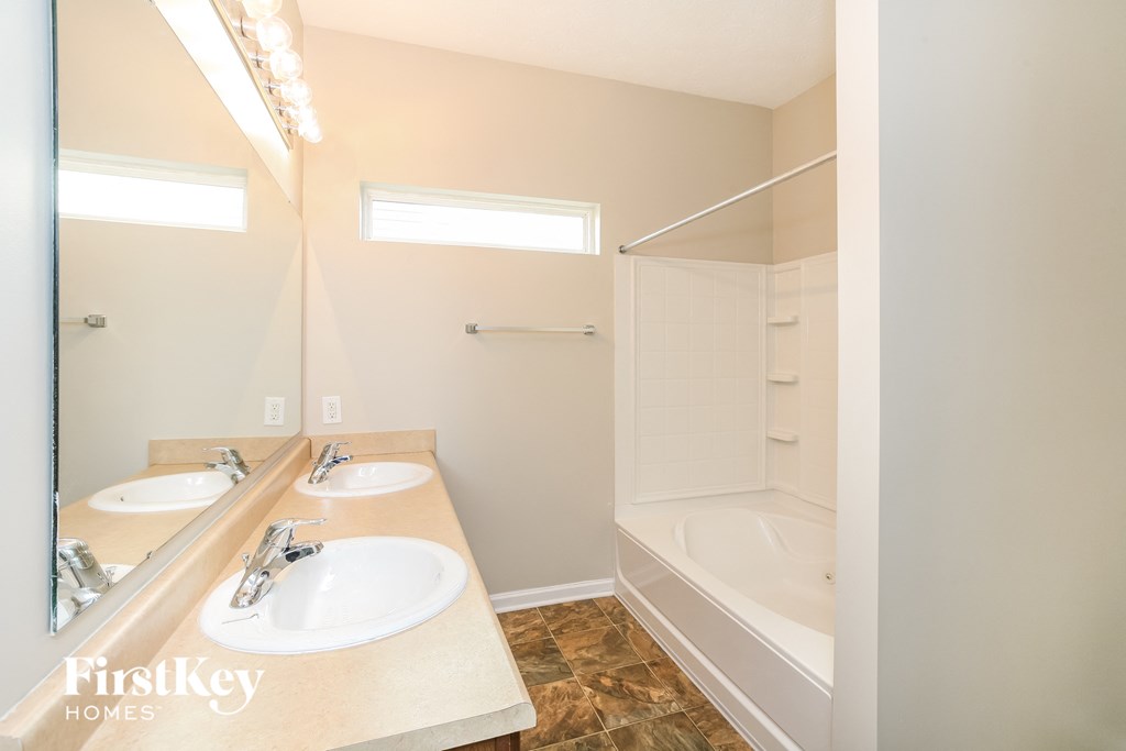 a bathroom with two sinks and a tub and a shower