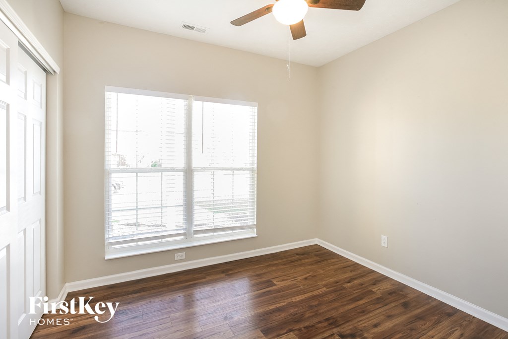 a living room with wood floors and a large window and a ceiling fan