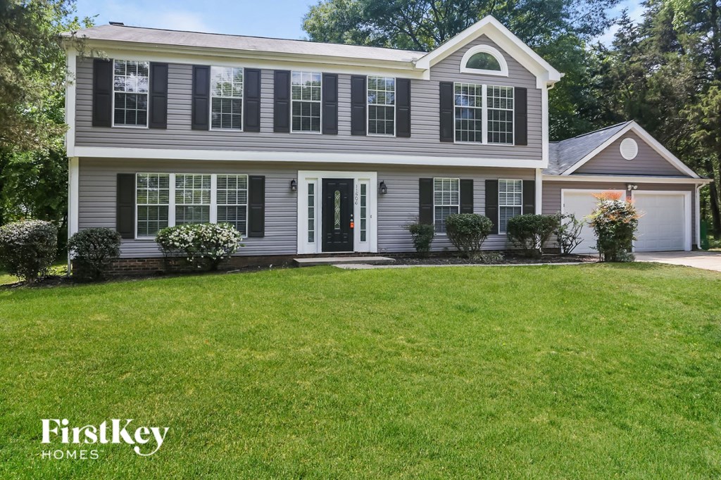 a white house with black shutters and a green lawn