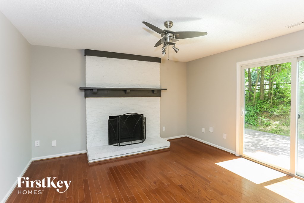 an empty living room with a fireplace and a ceiling fan